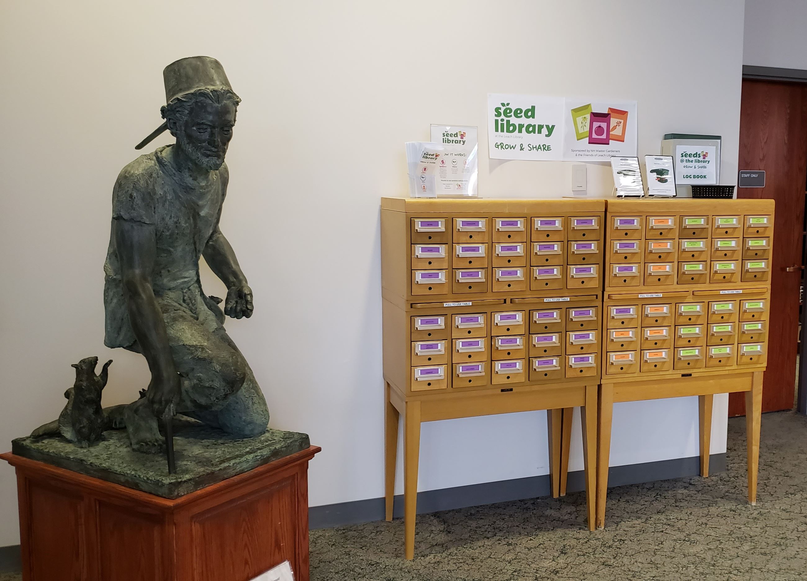 Leach Library Seed Library (two card catalogs beside Johnny Appleseed sculpture)