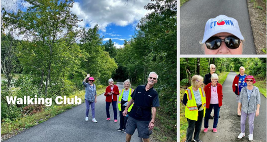 A group of happy seniors walking on a paved trail through the woods